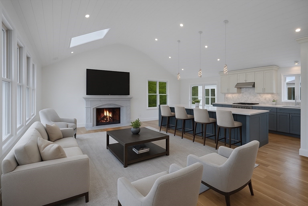 a living room with furniture a fireplace a flat screen tv and kitchen view