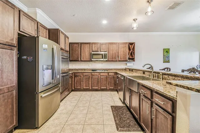 a large kitchen with stainless steel appliances granite countertop a refrigerator and a sink