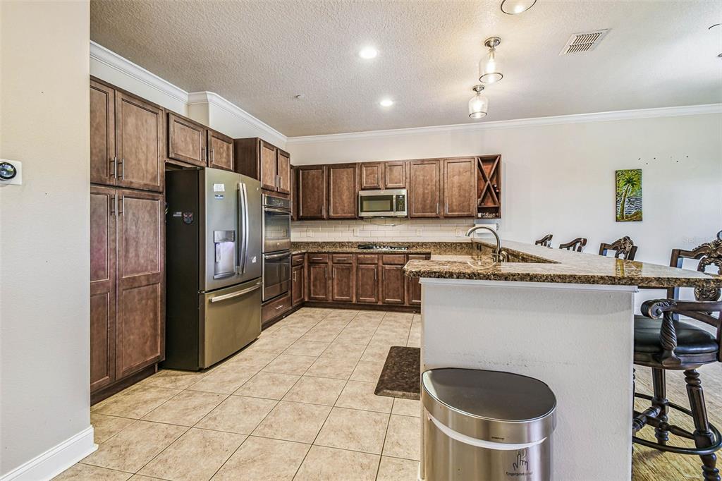 6533 Channelside Drive New Port Richey, FL 34652 - Photo 6 of 44 a kitchen with stainless steel appliances granite countertop a refrigerator a stove a sink and a microwave