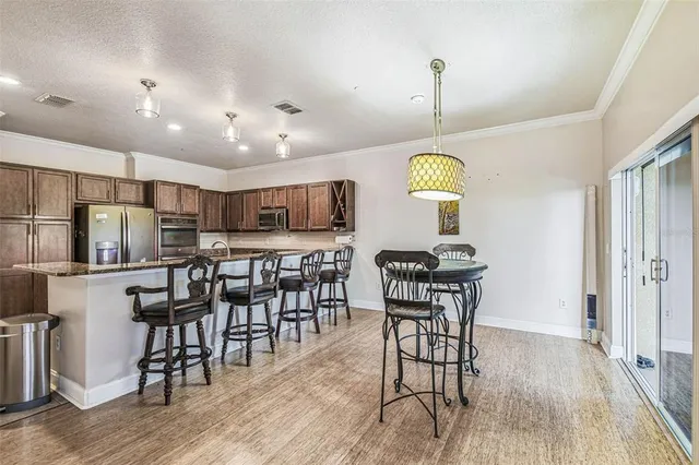 a kitchen with stainless steel appliances granite countertop a dining table chairs stove refrigerator and cabinets