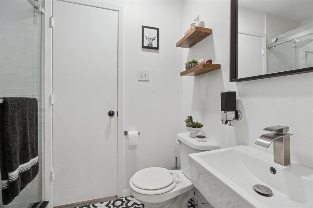 9780 Windy Ridge Road Frisco, TX 75033 - Photo 15 of 25 Bathroom featuring a vessel sink with a brushed nickel faucet, wall-mounted mirror with a black frame, and patterned floor tile
