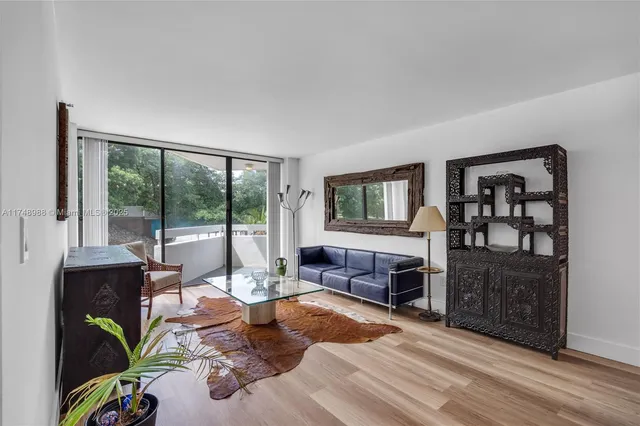 a living room with furniture a flat screen tv and a floor to ceiling window