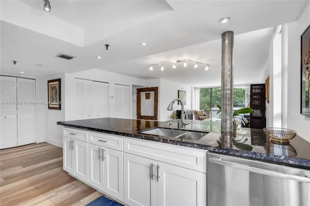 a kitchen with granite countertop a sink and white cabinets