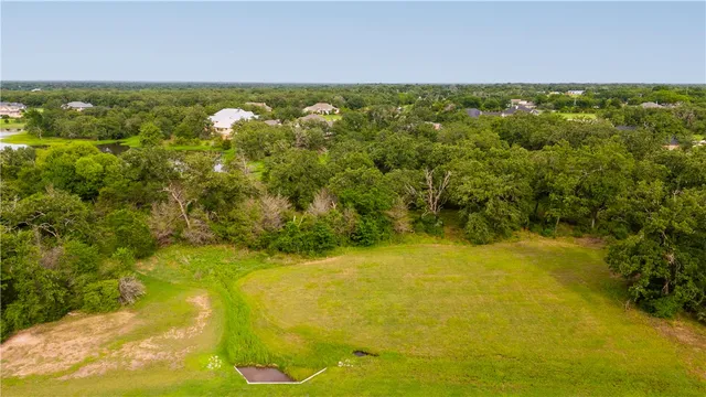 an aerial view of a residential houses with outdoor space and trees all around