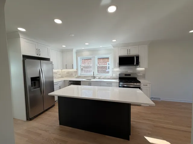 a large kitchen with stainless steel appliances a stove refrigerator a microwave oven with a sink and dishwasher