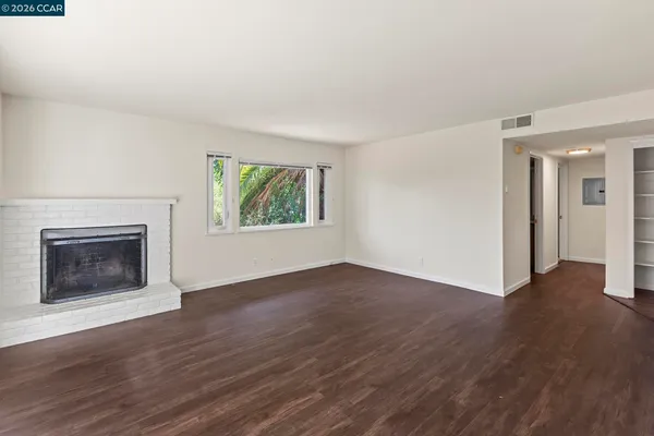 an empty room with wooden floor a fireplace and windows
