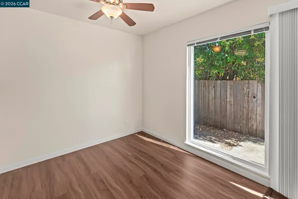 a view of an empty room with wooden floor and a window