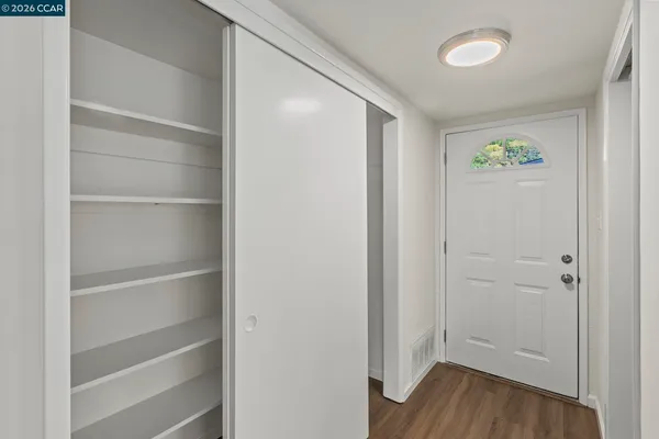 a view of an empty room with closet and wooden floor
