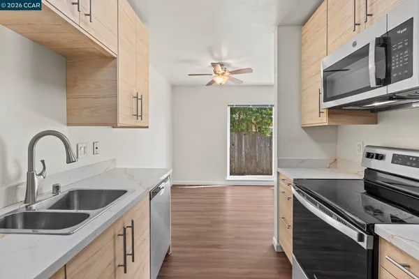 a kitchen with stainless steel appliances granite countertop a sink dishwasher a stove and a microwave oven with wooden floor