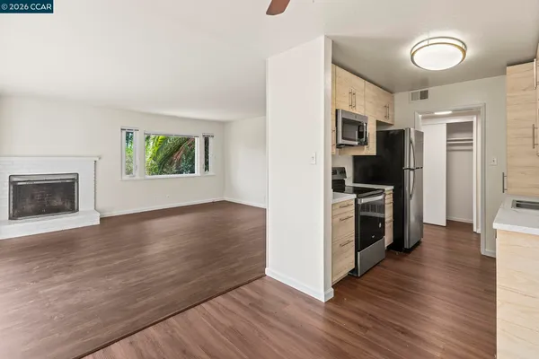 a view of kitchen with stainless steel appliances wooden floor and window
