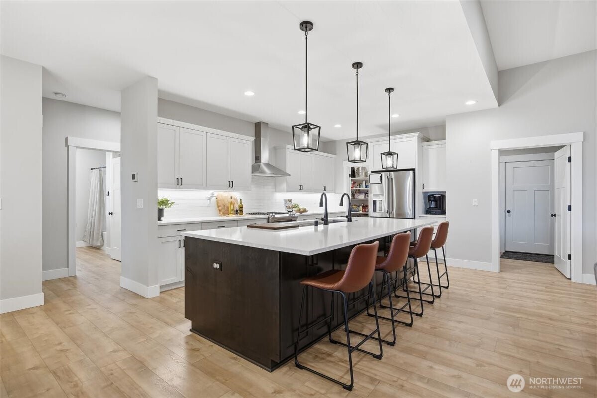 6915 Lamb Court Pasco, WA 99301 - Photo 10 of 40 a kitchen with kitchen island granite countertop a sink a center island a counter space and a refrigerator
