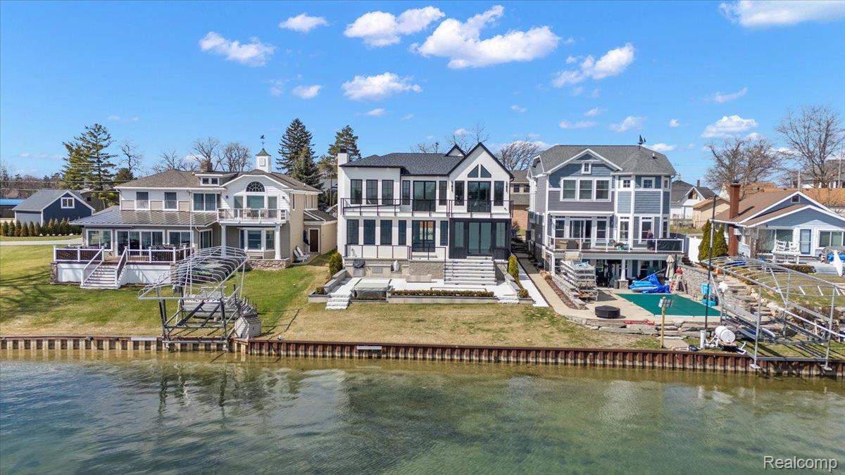 Back of house with a residential view, a water view, and a balcony