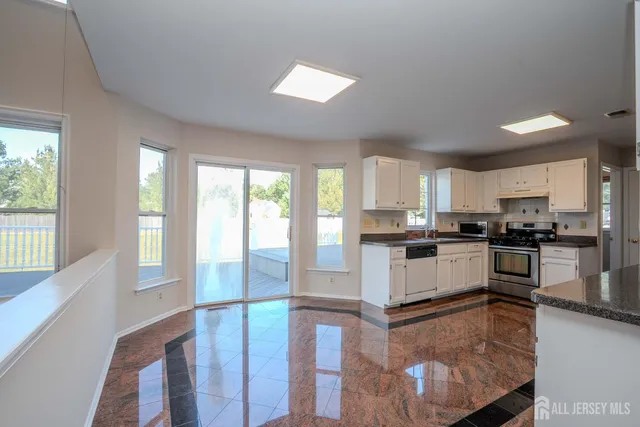 a kitchen with granite countertop a sink a window appliances and white cabinets