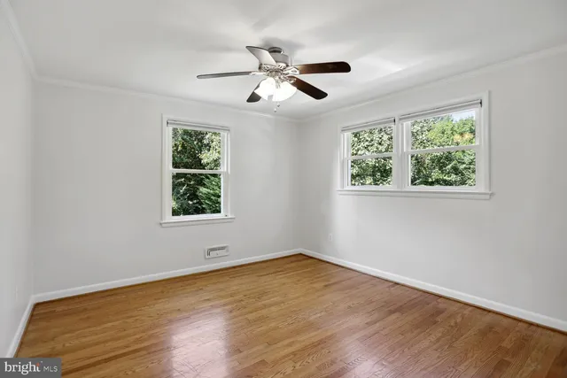 a view of empty room with wooden floor and fan