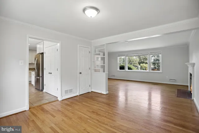 a view of an empty room with wooden floor and a window