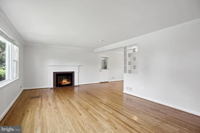 an empty room with wooden floor fireplace and windows