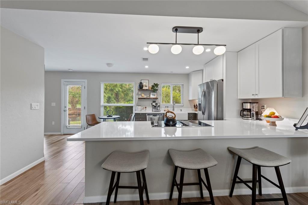 843 Palm View Drive, Unit 25 Naples, FL 34110 - Photo 3 of 27 a kitchen with stainless steel appliances a dining table chairs and wooden floor