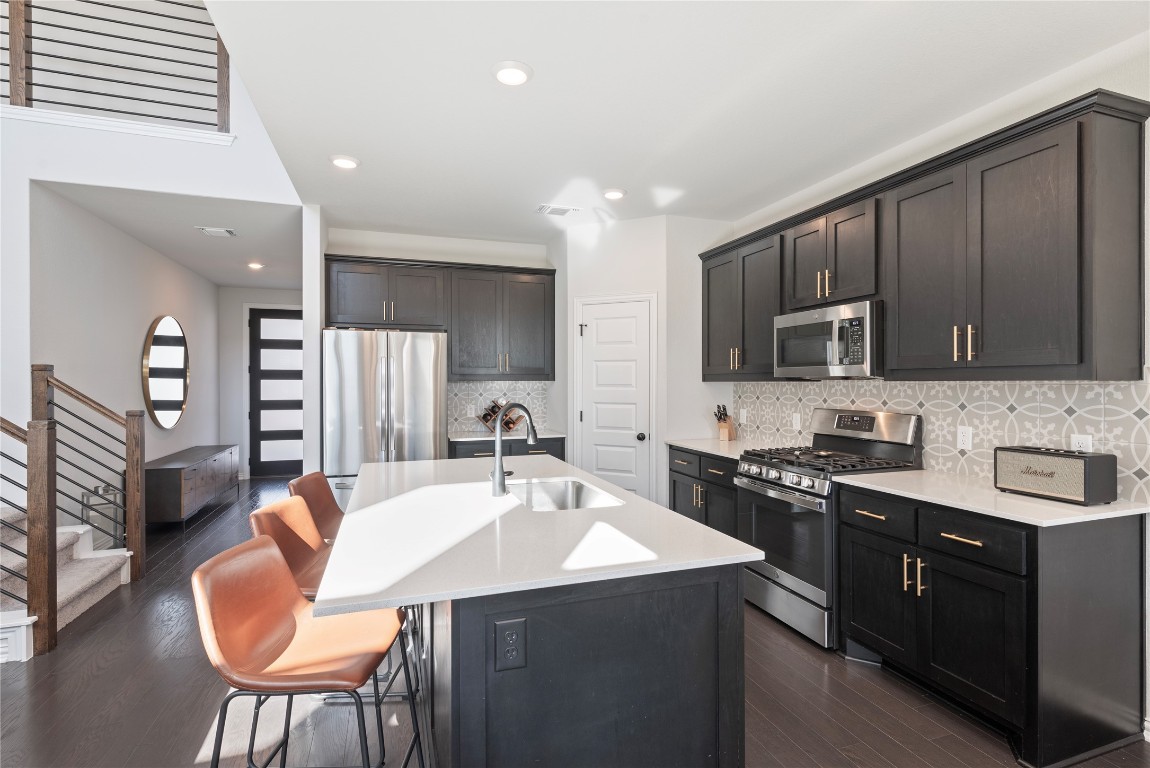 261 Fawn Riv Run Kyle, TX 78640 - Photo 8 of 40 a kitchen with stainless steel appliances granite countertop a sink dishwasher a stove a refrigerator with a dining table and chairs