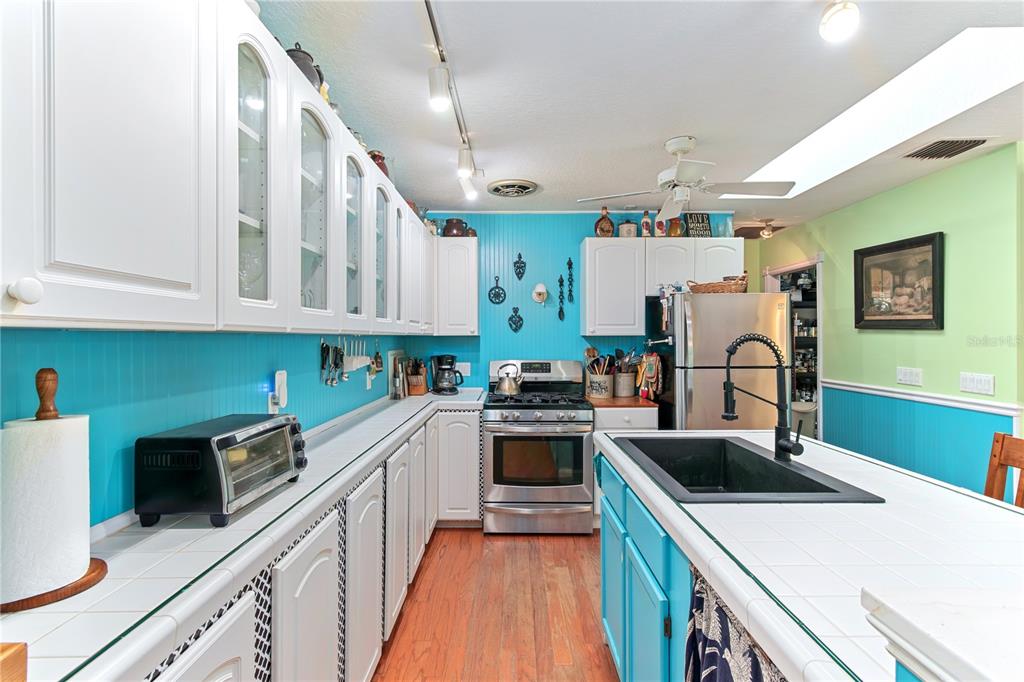 17840 Northeast 45th Avenue Road Citra, FL 32113 - Photo 24 of 62 a kitchen with kitchen island a stove a sink dishwasher and white cabinets with wooden floor