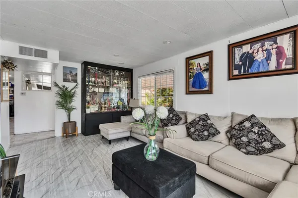 a living room with couches a coffee table and kitchen view with wooden floor