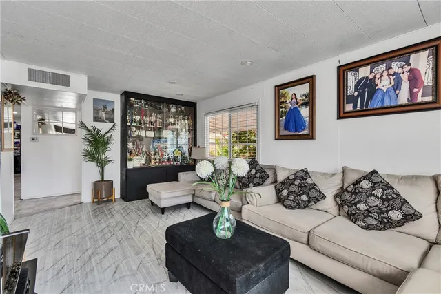a living room with couches a coffee table and kitchen view with wooden floor