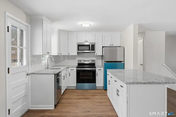 a kitchen with granite countertop a sink stove and refrigerator