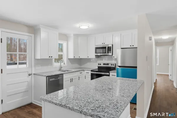 a kitchen with kitchen island granite countertop a sink stove and refrigerator