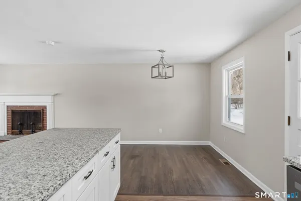 an empty room with a kitchen and a fireplace