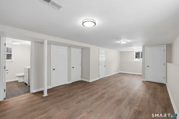 a view of an empty room with wooden floor and a toilet