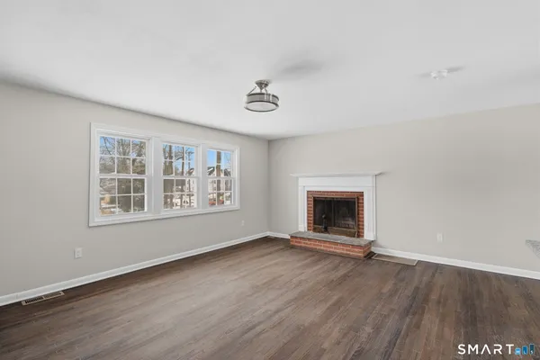 an empty room with large windows and a fireplace