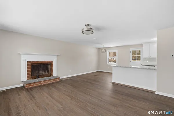 an empty room with wooden floor a fireplace and windows