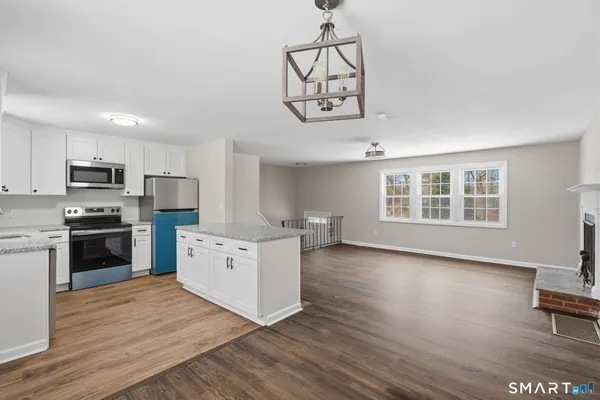 a kitchen with stainless steel appliances a white stove top oven a sink dishwasher and a refrigerator with wooden floor