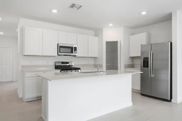 a kitchen with stainless steel appliances granite countertop a refrigerator a stove a microwave and a sink