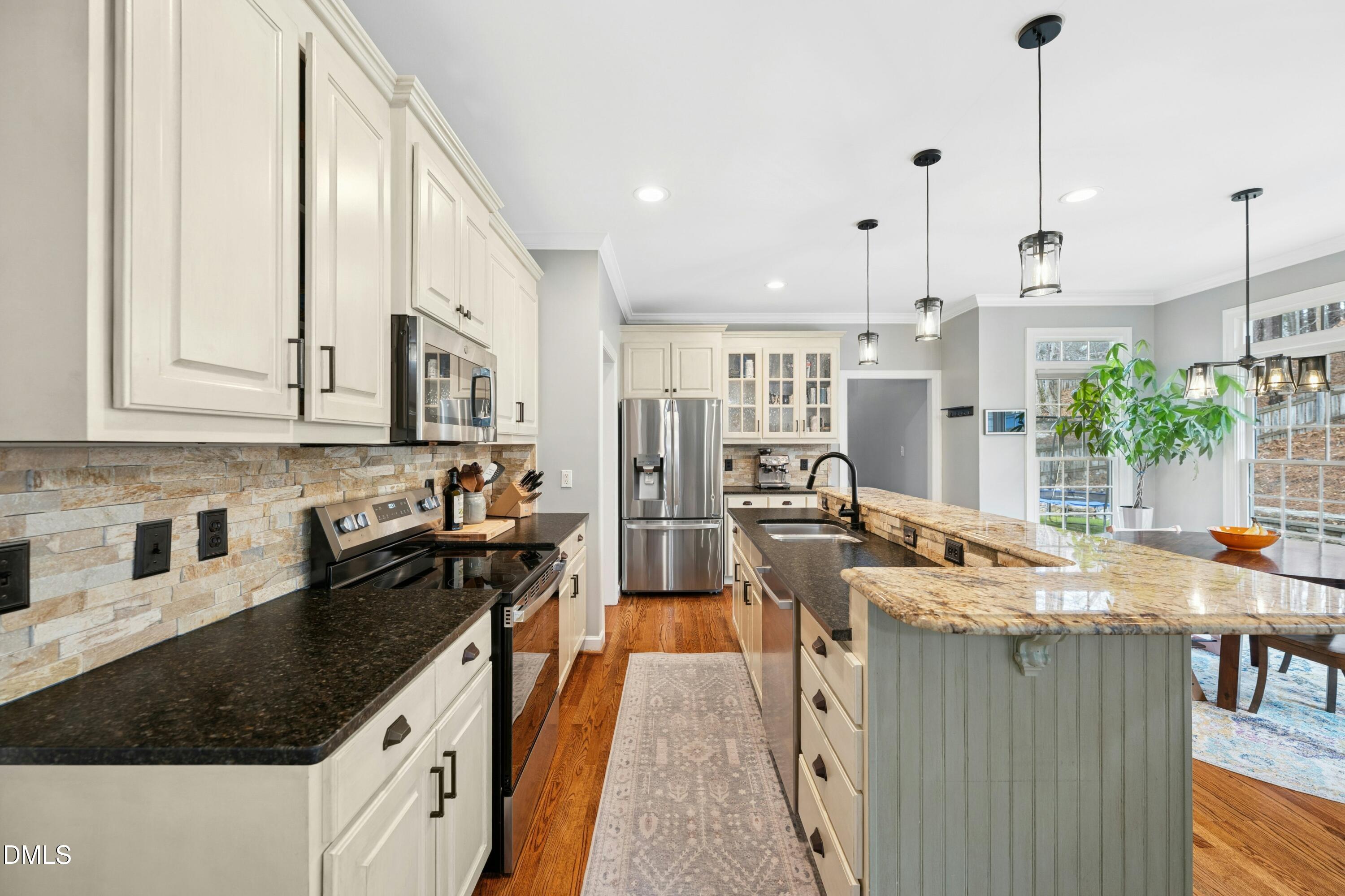 117 Barnes Spring Court Cary, NC 27519 - Photo 11 of 38 a kitchen with stainless steel appliances granite countertop a sink a stove and a wooden floors