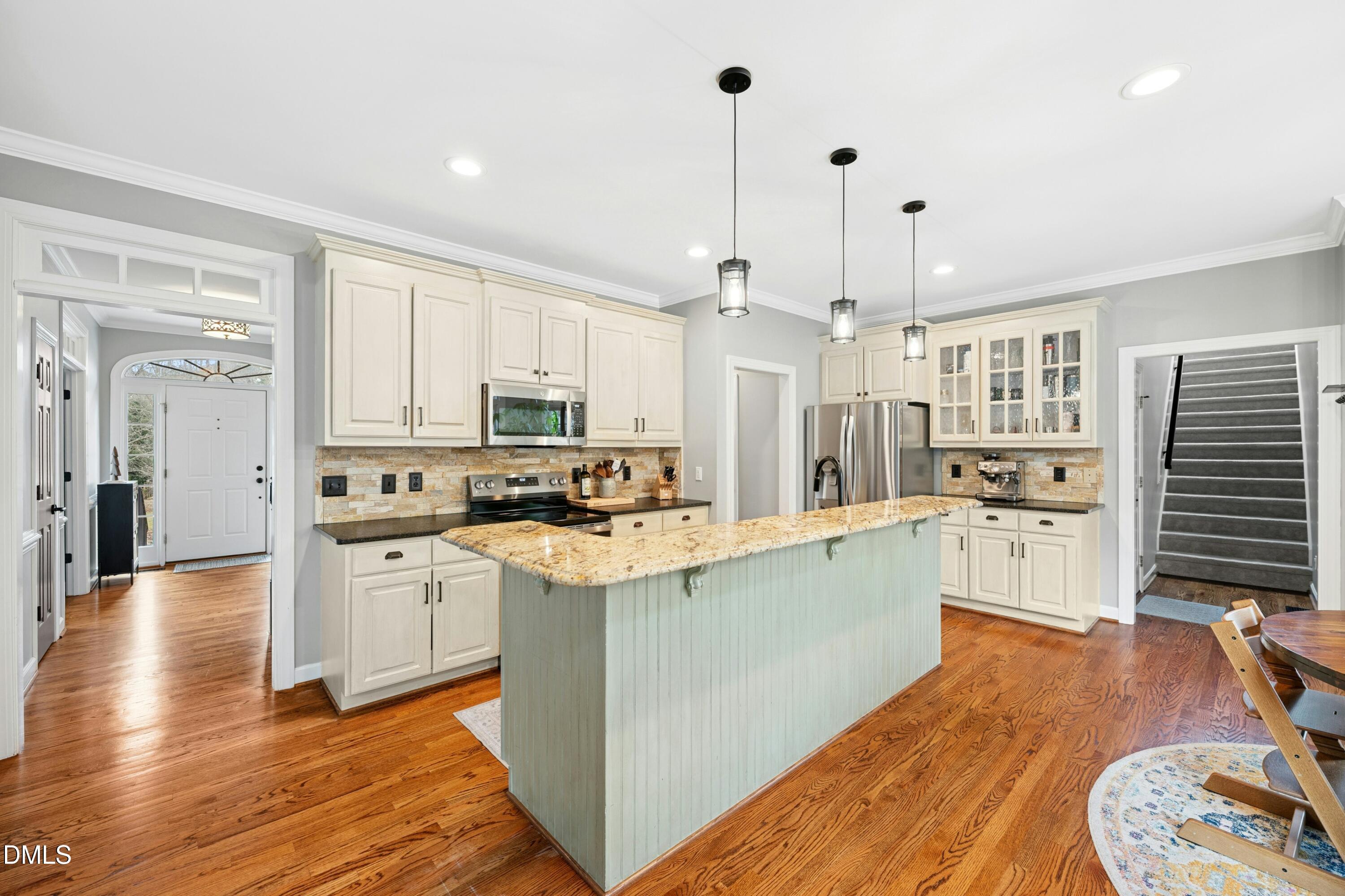 117 Barnes Spring Court Cary, NC 27519 - Photo 12 of 38 a kitchen with stainless steel appliances kitchen island wooden floors and white cabinets