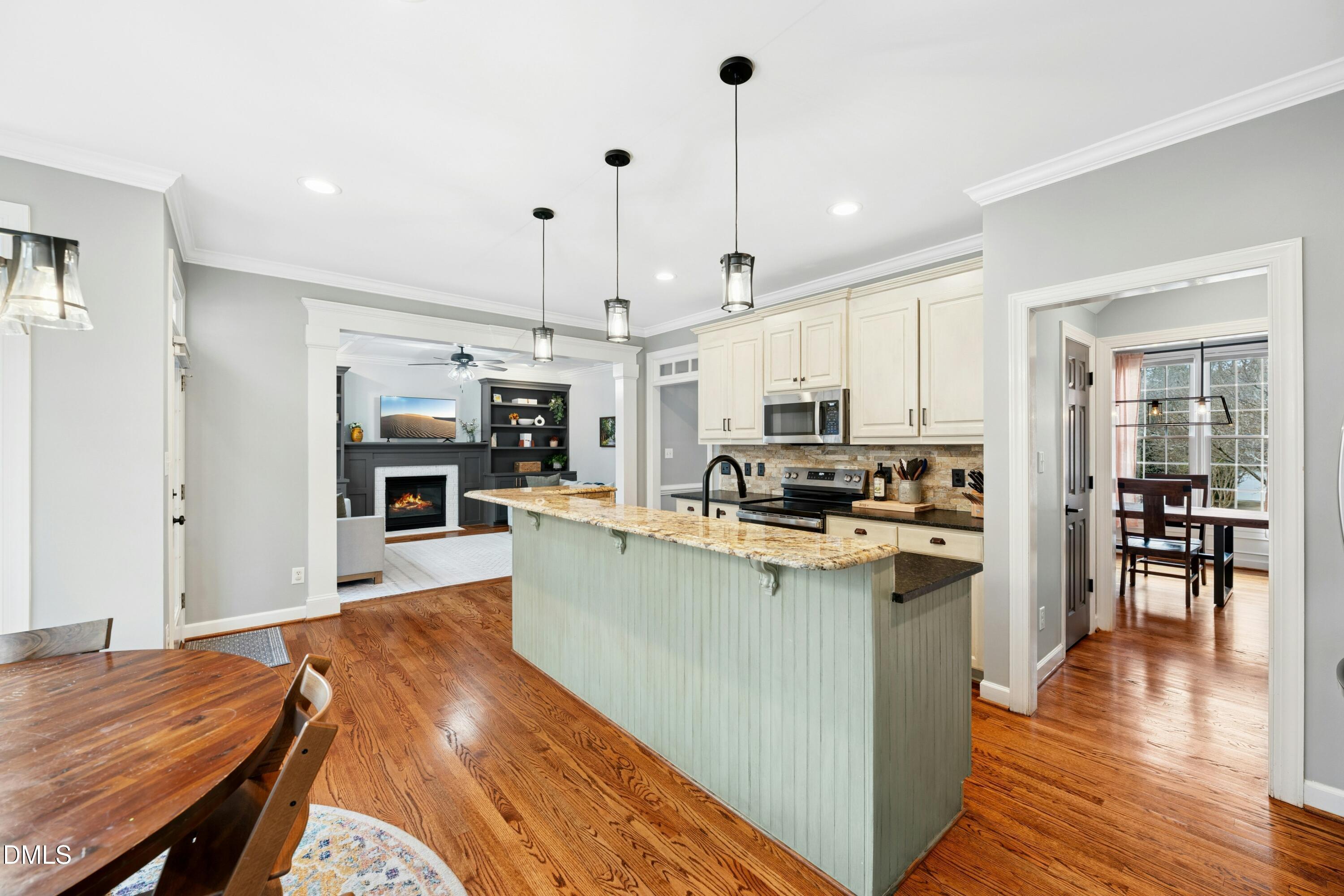 117 Barnes Spring Court Cary, NC 27519 - Photo 13 of 38 a kitchen with stainless steel appliances kitchen island granite countertop a refrigerator a stove top oven a sink dishwasher and a dining table with wooden floor