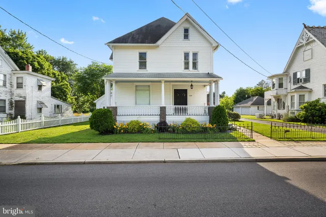 a view of a white house with a big yard and potted plants