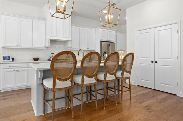 a kitchen with stainless steel appliances granite countertop a dining table chairs and white cabinets