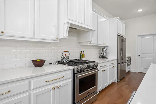 a kitchen with stainless steel appliances granite countertop white cabinets and a stove