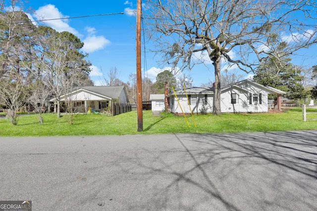 a view of a house with a yard and large tree