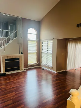 an empty room with wooden floor fireplace and windows