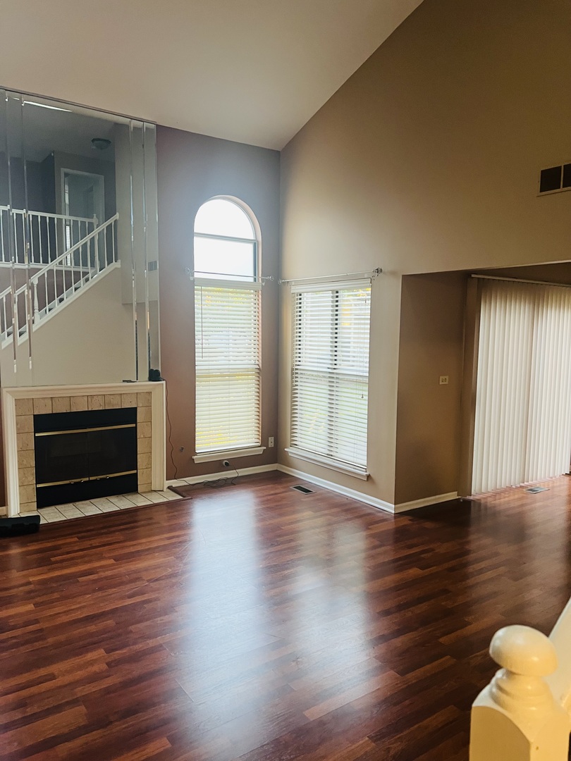 1042 Ridgefield Circle, Unit 1042 Carol Stream, IL 60188 - Photo 3 of 13 an empty room with wooden floor fireplace and windows