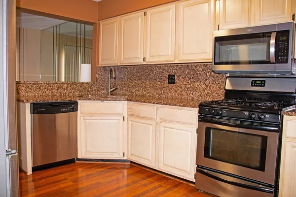a kitchen with granite countertop a stove top oven microwave and cabinets