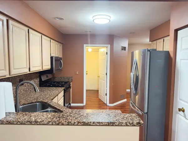 a kitchen with stainless steel appliances granite countertop a refrigerator a stove and a sink
