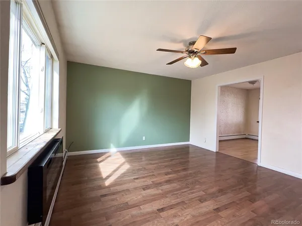 a view of empty room with wooden floor and fan