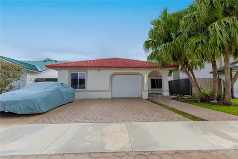 a view of a house with a yard and palm trees