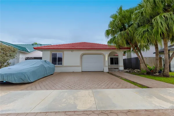a view of a house with a yard and palm trees