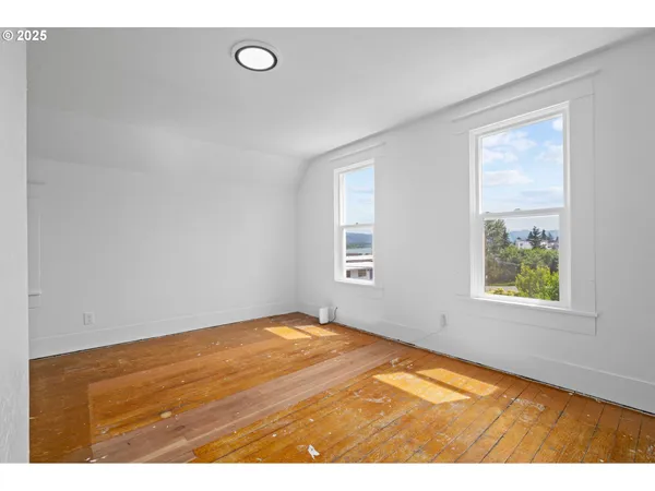 a view of empty room with window and wooden floor