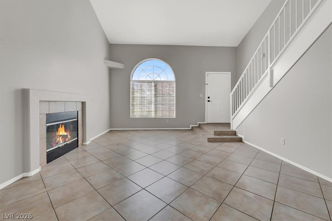 10148 Tree Bark Street Las Vegas, NV 89183 - Photo 7 of 37 A spacious living area offers a warm fireplace, arched window, and durable tile flooring leading to a stairway.