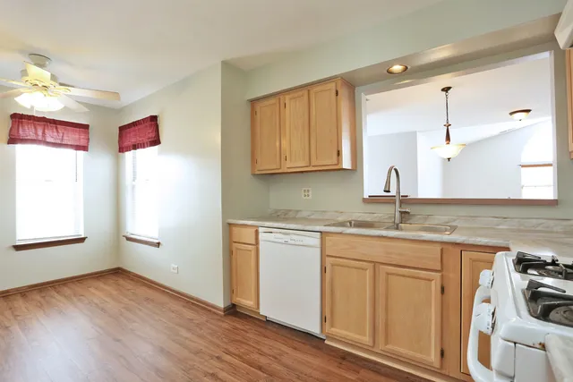 a kitchen with stainless steel appliances granite countertop a sink cabinets and wooden floor